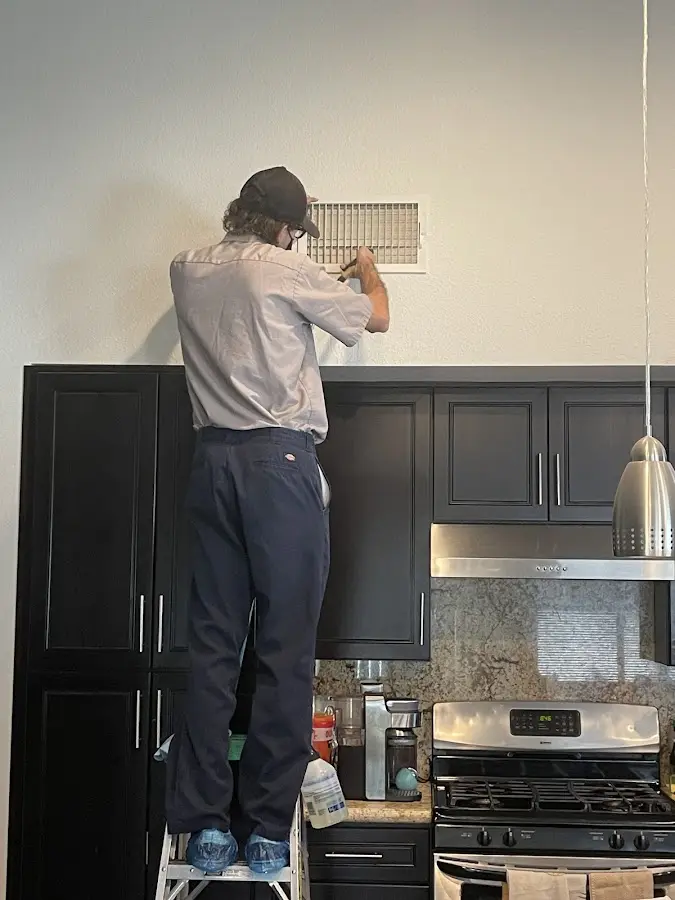 Technician inspecting an air vent during HVAC service in Huntersville